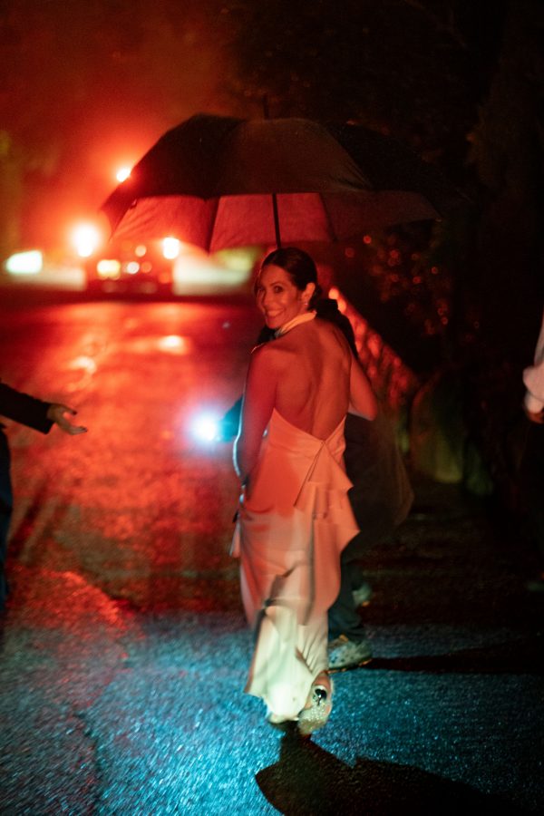 December Bride walking to her after party in the rain in the dark.